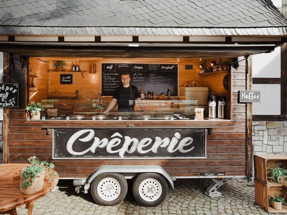 Rusticaler Crêperie Foodtruck mit zwei sympathischen Servicekräften bei einem Hochzeitscatering in Köln